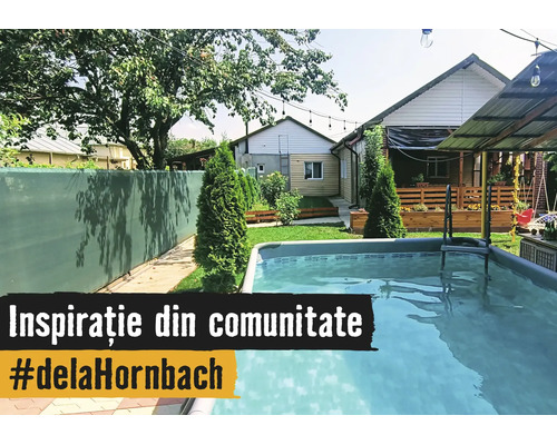 O grădină luminoasă cu o piscină supraterană dreptunghiulară, paravan verde, gazon cu tuia și o terasă din lemn în fața casei.