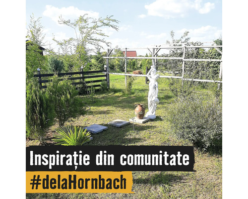 Grădină luminoasă cu o statuie albă, dale de piatră, plante decorative și un gard din lemn.