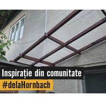 Copertină pentru terasă cu cadru din lemn și plăci translucide montată pe peretele exterior al casei.