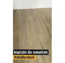 Pardoseală laminată cu aspect de lemn, nervuri naturale și plăci late, montată cu plintă.