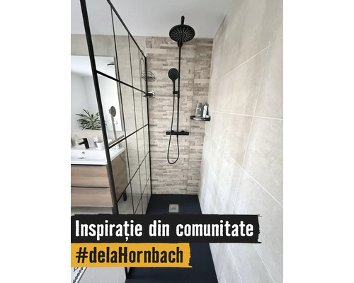 Baie modernă cu perete de duș din sticlă în stil industrial, sistem de duș negru, gresie cu aspect de piatră și mască de lavoar din lemn.