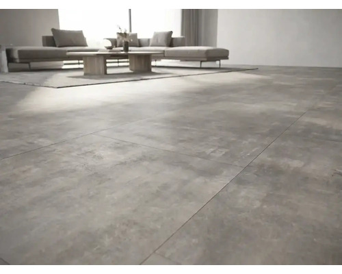 Cameră de zi modernă cu plăci de gresie de format mare cu aspect de beton, canapea gri și masă din lemn.