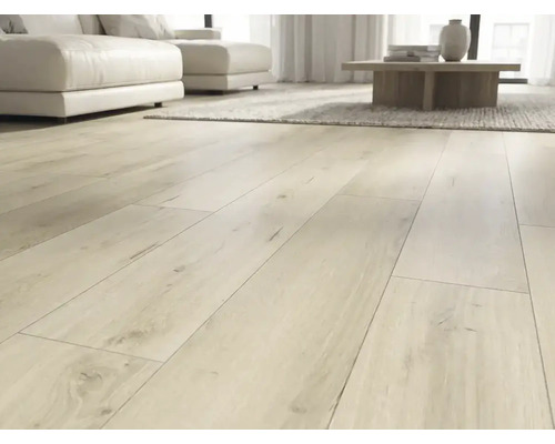 Pardoseală laminată deschisă la culoare cu aspect de stejar montată ca placă rustică într-o cameră de zi modernă și luminoasă cu canapea albă.