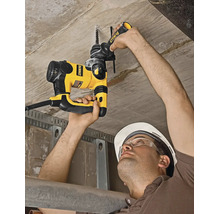 Un muncitor găurește un tavan de beton cu un ciocan rotopercutor DeWalt, purtând cască de protecție și ochelari.