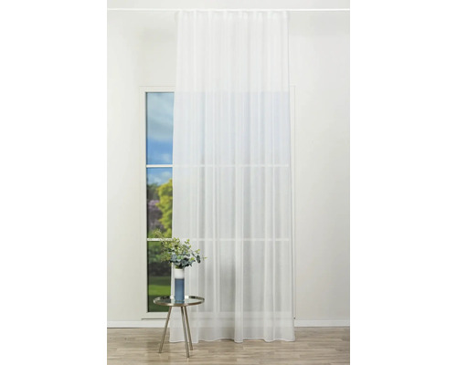 O perdea semitransparentă atârnă la fereastră într-o cameră luminoasă, cu un design modern, având o masă laterală și o plantă.