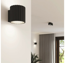 Lampă de perete modernă cu structură canelată de formă cilindrică pentru iluminarea livingului într-un interior elegant.