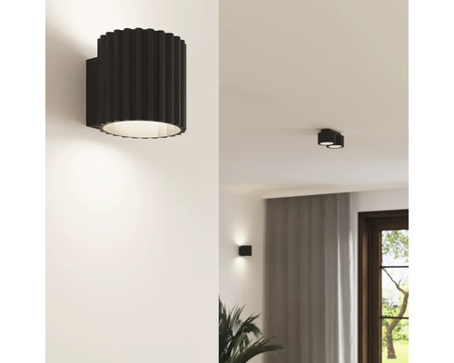 Lampă de perete modernă cu structură canelată de formă cilindrică pentru iluminarea livingului într-un interior elegant.