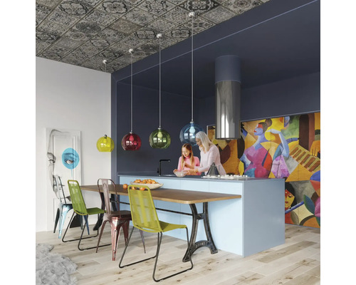Bucătărie modernă cu insulă de bucătărie, lămpi suspendate colorate, tavan cu model și decor abstract pe perete, unde oamenii gătesc împreună.