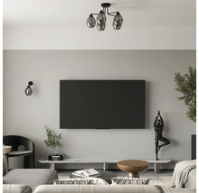 Living modern cu televizor plat, o lampă de tavan cu patru globuri de sticlă, aplică de perete, comodă TV din marmură și figurină decorativă.