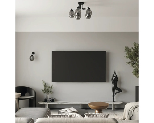 Living modern cu televizor plat, o lampă de tavan cu patru globuri de sticlă, aplică de perete, comodă TV din marmură și figurină decorativă.