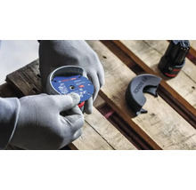Persoană cu mănuși de protecție montează un disc de tăiere Bosch Expert cu diametrul de 76 milimetri pe un polizor unghiular cu acumulator.