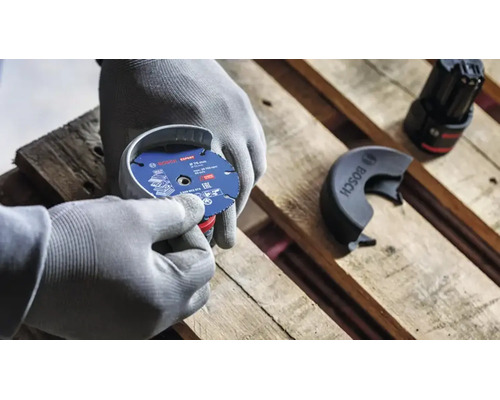 Persoană cu mănuși de protecție montează un disc de tăiere Bosch Expert cu diametrul de 76 milimetri pe un polizor unghiular cu acumulator.