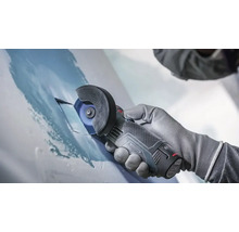 Mana in manusa de protectie tine un polizor unghiular cu acumulator Bosch in timp ce taie o suprafata metalica