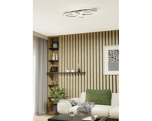 Plafonieră modernă cu inele LED într-un living amenajat cu stil, cu perete din lamele de lemn și canapea confortabilă.
