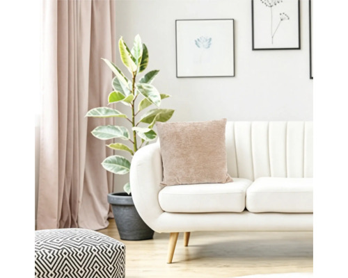 Living cu canapea moderna, perna bej, planta de interior si taburet geometric intr-un interior luminos si primitor.