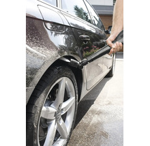 O persoană curăță pasajul roții unui autoturism cu un aparat de spălat cu înaltă presiune și o duză Kärcher specială pentru întreținerea auto.