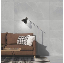 Living cu gresie mare cu aspect de piatră pe perete, canapea maro, măsuță de cafea și lampadar într-un design interior modern.