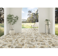 Terasă acoperită cu plăci ceramice cu aspect de piatră naturală, vedere către o grădină cu un șezlong, un ghiveci și o vază pe suport.