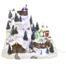 Scenă de sat de iarnă de Crăciun cu case, schiori și brazi pe un deal acoperit de zăpadă