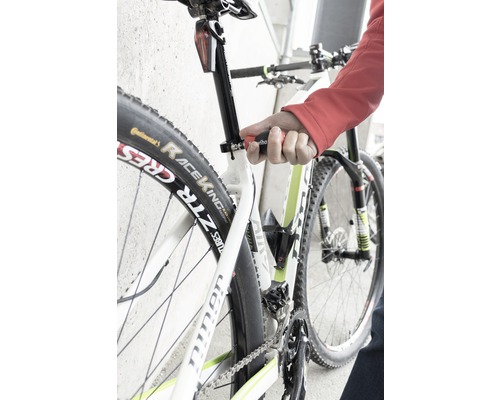 Prim-plan cu o bicicletă a cărei tijă de șa este reglată cu o unealtă.