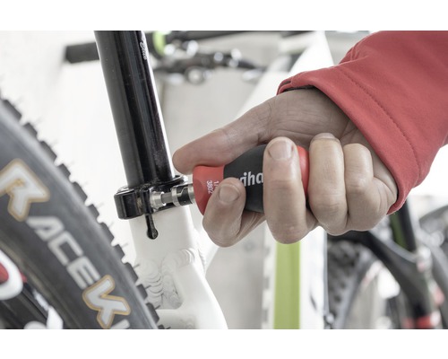 Un bărbat folosește o șurubelniță Wiha pe o bicicletă.