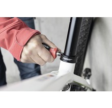 O persoană folosește o unealtă pe o bicicletă pentru reparații.