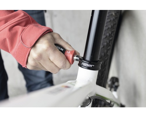 O persoană folosește o unealtă pe o bicicletă pentru reparații.