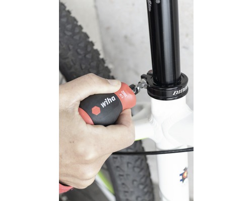 O persoană fixează o tijă de șa de bicicletă cu o șurubelniță Wiha.