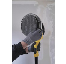 O persoană folosește o șlefuitoare de gips-carton pe un perete.