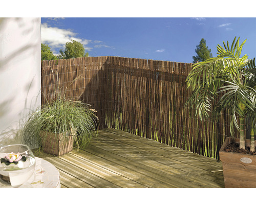 Terasa cu paravan din stuf, podea din lemn și plante la ghiveci.