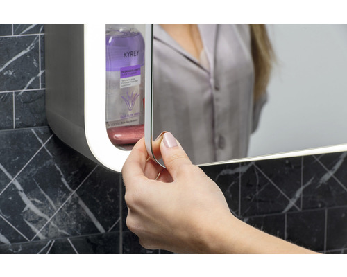 Femeie deschizând dulap cu oglindă în baie