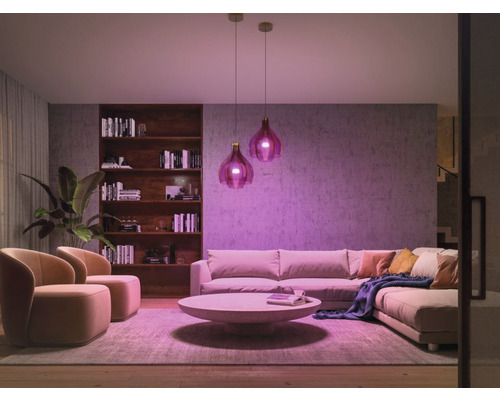 Living luminos cu canapea, fotolii, măsuță de cafea, bibliotecă și două lămpi suspendate pentru o atmosferă primitoare.