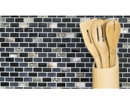 Ustensile de bucătărie din lemn într-un recipient în fața unui perete mozaic
