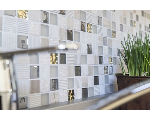 Prim-plan cu un perete cu plăci de mozaic și o plantă în ghiveci.