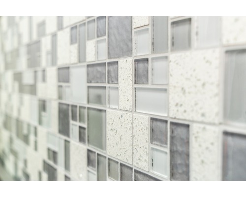 Prim-plan cu un perete cu plăci de mozaic în diferite nuanțe de gri și texturi.