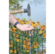 Persoană bate un stâlp într-un gard de grădină cu un ciocan