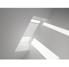 Fereastră de mansardă cu jaluzea plisată într-o cameră luminoasă