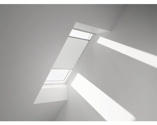 Fereastră de mansardă cu jaluzea plisată într-o cameră luminoasă