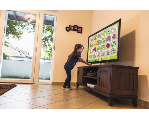 Copil se joacă cu un televizor pe un dulap TV în camera de zi.