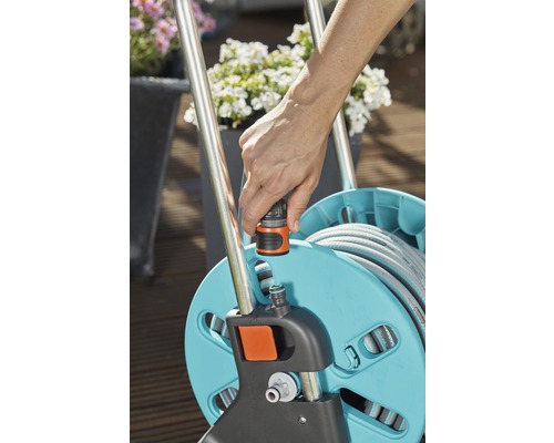 O persoană conectează un furtun de grădină la o rolă de furtun.