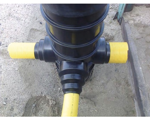 Vedere de sus a unui canal de scurgere a apei pluviale negru cu țevi galbene