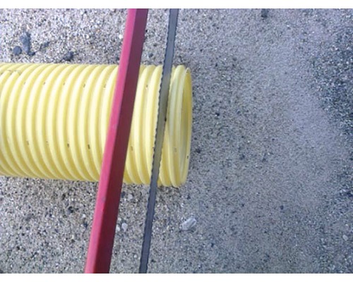 Tubulatură ondulată galbenă tăiată cu un fierăstrău pentru metal.