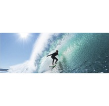 Un surfer călărește un val sub un cer senin.