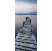 Pasarelă din lemn care duce spre apă cu peisaj montan în fundal