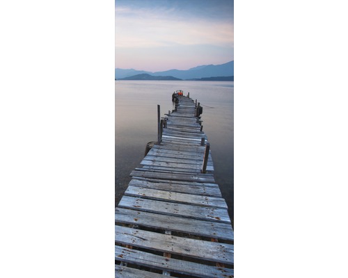 Pasarelă din lemn care duce spre apă cu peisaj montan în fundal