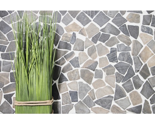 Tufe decorative de iarbă în fața unui perete din imitație de piatră naturală.