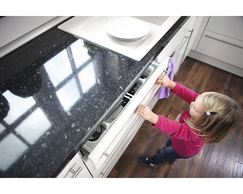 Un copil mic deschide un sertar de bucătărie cu un suport pentru cuțite.