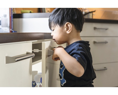 Copil care încearcă să deschidă un sertar cu blocare de siguranță pentru copii