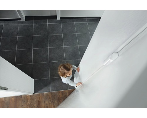 Vedere a camerei cu un copil lângă o plintă de încălzire.