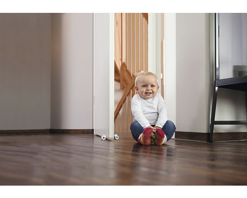 Un copil stă pe podea în fața unei bariere de scări.